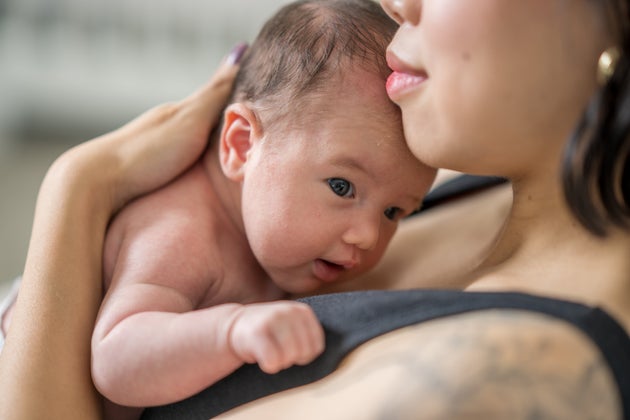 A sweet newborn baby lays skin-to-skin on her mothers chest as they rest in the nursery together.