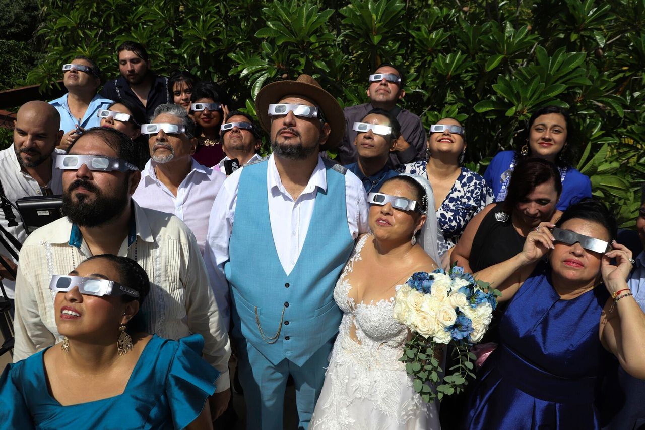 Νεόνυμφοι, συγγενείς και καλεσμένοι του γάμου παρακολοθούν με ειδικά γυαλιά την ηλιακή έκλειψη, γνωστή και ως «δαχτυλίδι της φωτιάς» λίγο πριν τη γαμήλια τελετή - Μέριδα, Μεξικό.