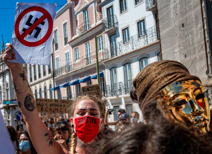 A protester wears a protective mask and holds an anti-Nazi sign during a rally to demonstrate against fascism, Nazism and racism on July 25, 2020, in Lisbon, Portugal.