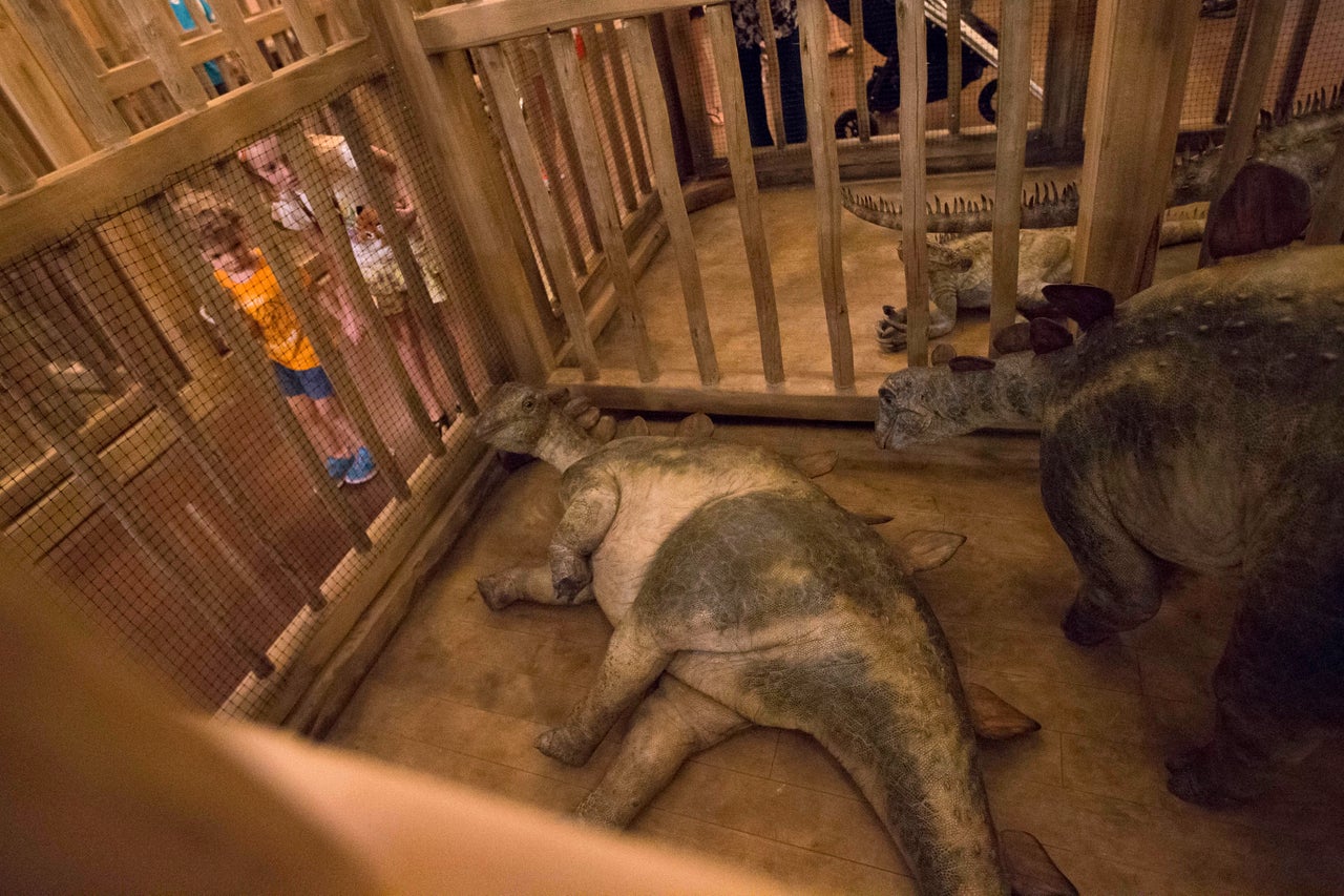 Children look into a cage containing model baby dinosaurs inside a replica Noah's Ark at the Ark Encounter theme park in Williamstown, Kentucky.