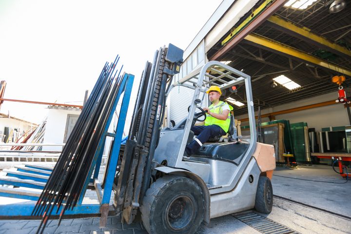 young man using forklift in factory
