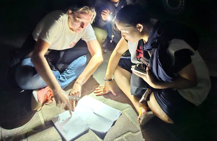 ガザ南部に避難中に懐中電灯の下、夜間の打ち合わせをする様子（右が白根さん）