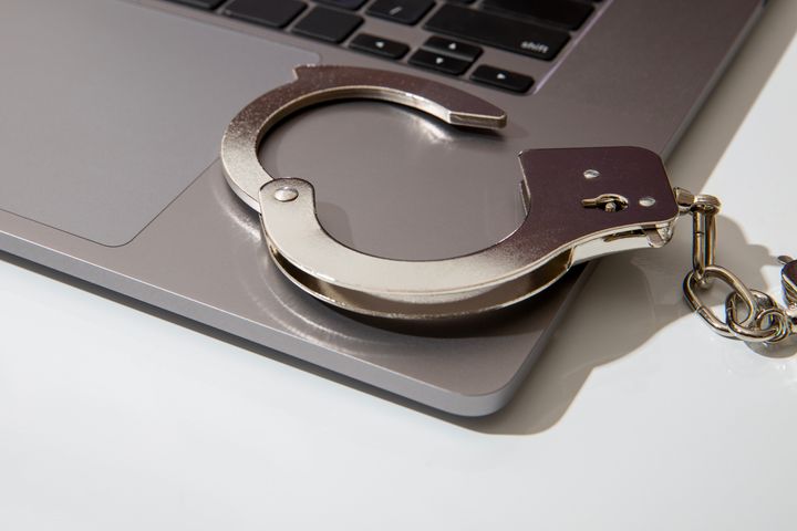 Handcuff close-up on top of a laptop with white background