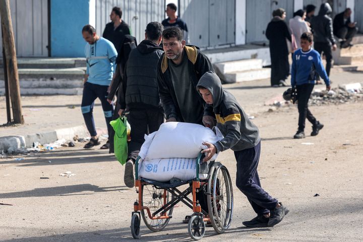 A man and a boy push a wheelchair carrying sacks of flour that their family received from a warehouse of the U.N. Relief and Works Agency for Palestine Refugees (UNRWA) in Rafah in the southern Gaza Strip on Tuesday, amid continuing battles between Israel and the militant group Hamas. 