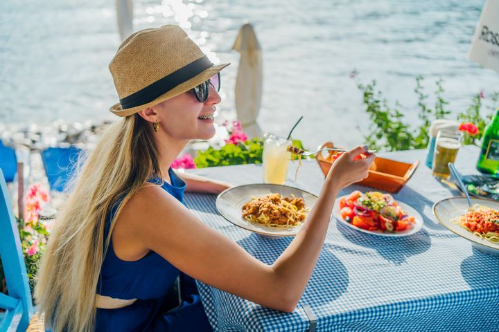Young cheerful woman having lunch in a seaside restaurant