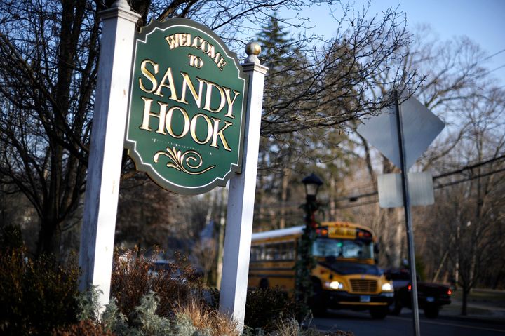 A bus drives past a sign reading "Welcome to Sandy Hook" in Newtown, Connecticut, where 26 people were fatally shot at an elementary school in 2012.
