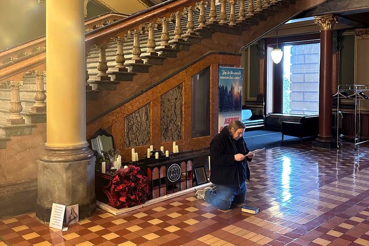 Ένας άνδρας απαγγέλλει χριστιανικές προσευχές σε μια κατεστραμμένη σατανιστική έκθεση στο Καπιτώλιο της πολιτείας της Αϊόβα, την Παρασκευή 15 Δεκεμβρίου 2023, στο Des Moines της Αϊόβα.
