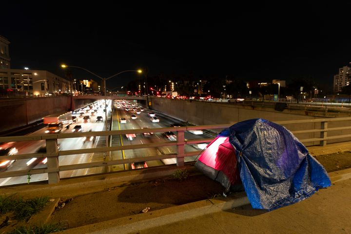 FILE - In this photo illuminated by an off-camera flash, a tarp covers a portion of a homeless person's tent on a bridge overlooking the 101 Freeway in Los Angeles, Thursday, Feb. 2, 2023. (AP Photo/Jae C. Hong, File)