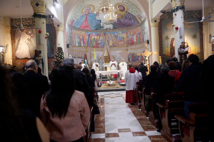 Ο πάτερ Gabriel Romanelli, Λατίνος ιερέας της ενορίας της Λωρίδας της Γάζας, στο κέντρο, διεξάγει τη μεταμεσονύκτια λειτουργία της παραμονής των Χριστουγέννων στην Καθολική Εκκλησία της Αγίας Οικογένειας Deir Al Latin στην πόλη της Γάζας, Παρασκευή 24 Δεκεμβρίου 2021.