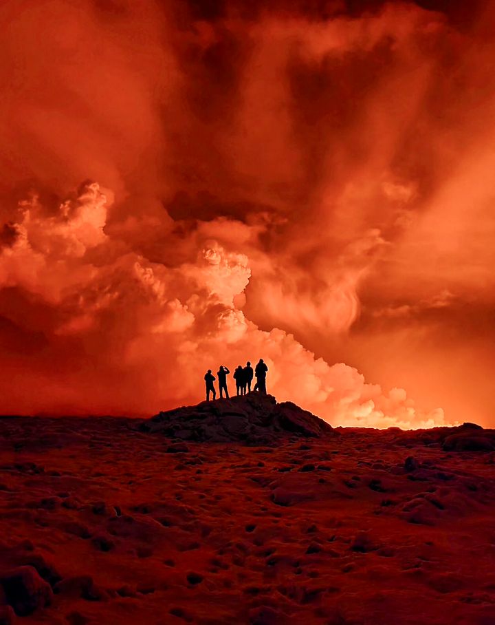 Local residents watch smoke billow from a volcanic eruption on the Reykjanes Peninsula on Tuesday.