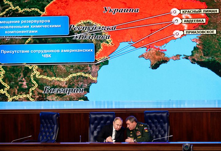 Ο Βλαντιμίρ Πουτιν και o αρχηγός του Γενικού Επιτελείου στρατού συνομιλούν έχοντας πίσω τους έναν ρωσικό στρατιωτικό χάρτη που δείχνει την υποτιθέμενη ανάπτυξη αμερικανικών δυνάμεων στην ανατολική Ουκρανία στις 21 Δεκεμβρίου 2021, ένα σχεδόν χρόνο προιν από την εισβολή.