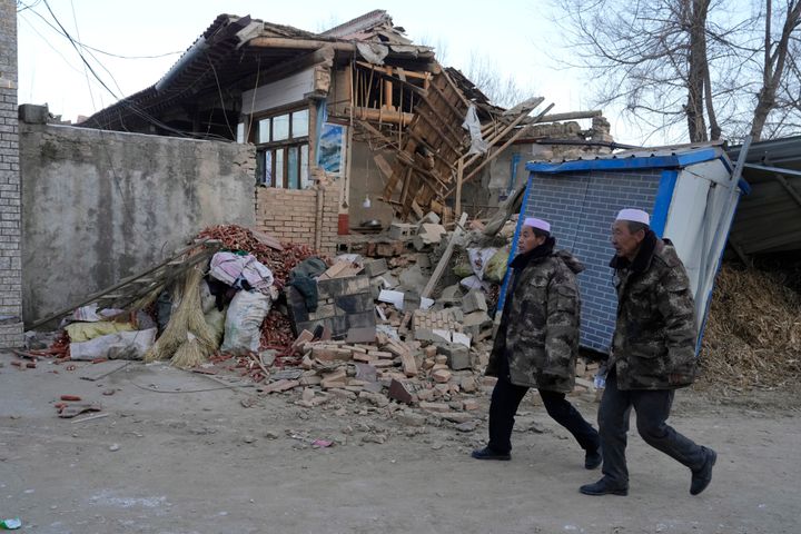 Residents walk by a collapsed house in Yangwa village near Dahejia town in northwestern China's Gansu province, on Dec. 20, 2023.