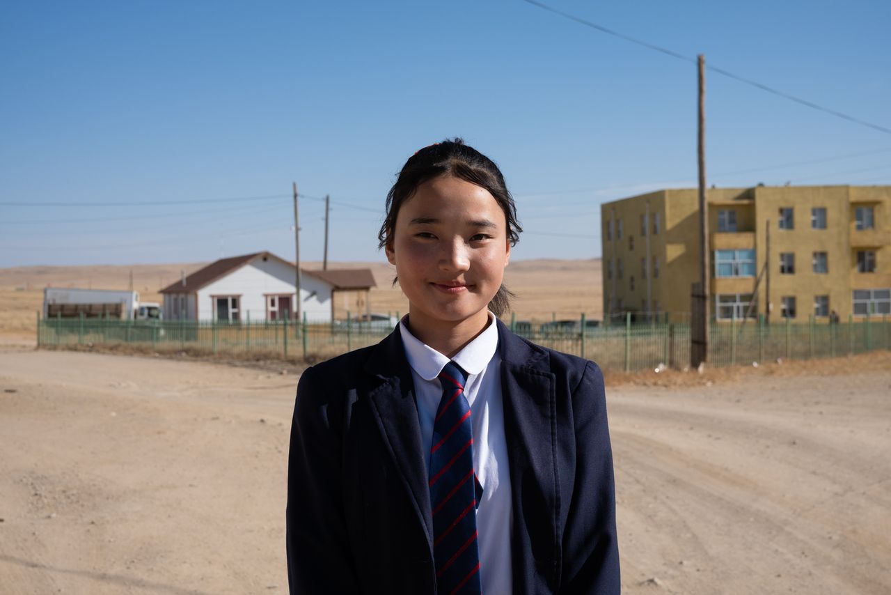 Minjinsor Ichinnorov, 15, here on a street outside her schoolhouse in October, spends most of her time in a dormitory in the Sant soum center. She used to travel by motorcycle to visit her parents on weekends, but now they travel so far in search of green grass that she loses contact with them for days. 