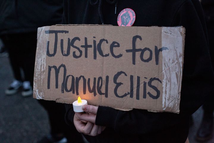 TACOMA, WA - JUNE 03: A person holds a sign during a vigil for Manuel Ellis, a black man whose March death while in Tacoma Police custody was found to be a homicide, according to the Pierce County Medical Examiners Office, near the site of his death on June 3, 2020 in Tacoma, Washington. (Photo by David Ryder/Getty Images)