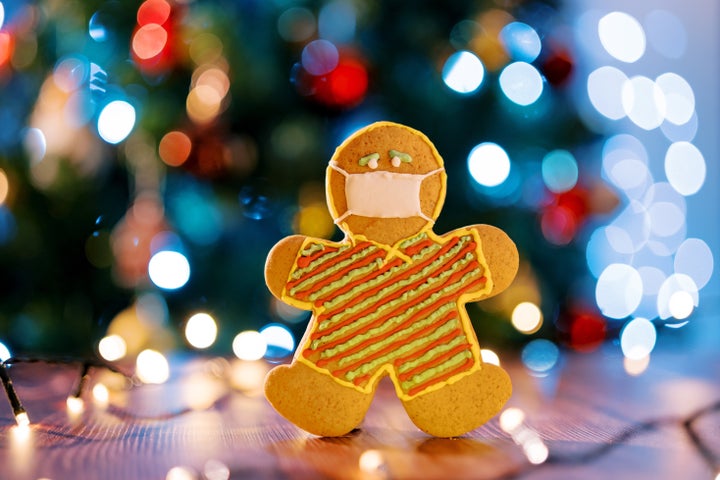 Cookie-man in a protective mask on the table near the sparkling garlands. High quality photo