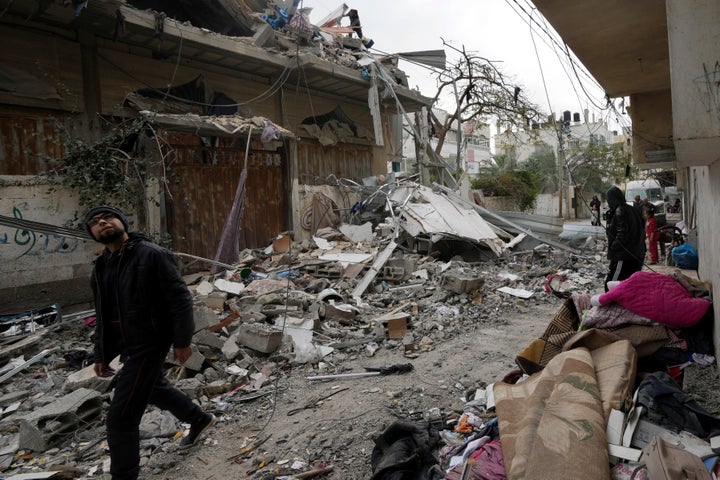 Palestinians look at the residential building of the Khalifa family destroyed in an Israeli strike in Nusseirat refugee camp, central Gaza Strip, Saturday, Dec. 23, 2023. (AP Photo/Adel Hana)