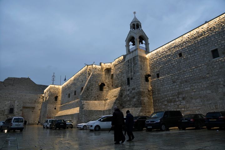 People walk by the Church of the Nativity, in the West Bank town of Bethlehem, Friday, Dec. 23, 2023. Bethlehem is having a subdued Christmas after officials in Jesus' traditional birthplace decided to forgo celebrations due to the Israel-Hamas war. (AP Photo/Mahmoud Illean)