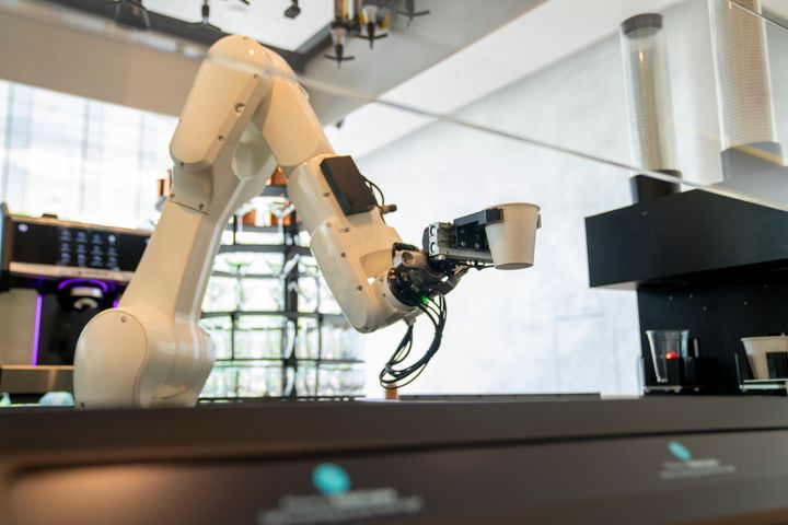 Robot arm serving hot coffee in a coffee shop.