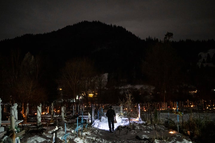 Ivan Zelenchuk walks to visit the graves of his relatives at the cemetery in Kryvorivnia village, Ukraine, Sunday, Dec. 24, 2023. (AP Photo/Evgeniy Maloletka)