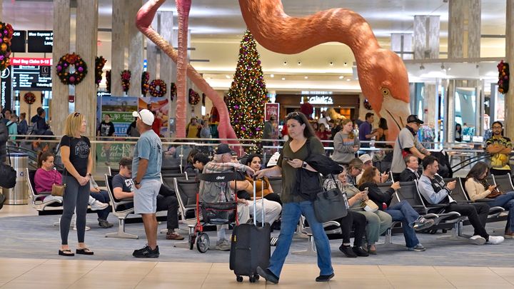 FILE - Holiday travelers pass by "Phoebe" the Flamingo at the Tampa International Airport, Friday, Dec. 22, 2023, in Tampa, Fla. Conditions were mostly nice for travelers flying ahead of and on Christmas Day this year, but some naughty disruptions plagued those flying with Southwest Airlines again this year. By midday Monday, Dec. 25, only 138 flights within, into or out of the U.S. had been canceled and 1,366 were delayed, according to FlightAware, a tracking website. (AP Photo/Chris O'Meara, File)