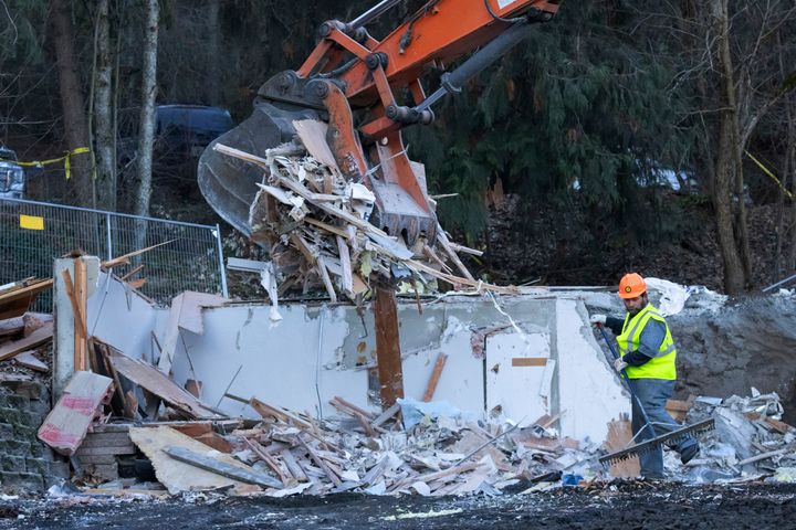 A worker rakes debris during a pause in the use of heavy equipment to demolish the house where four University of Idaho students were killed in 2022. 