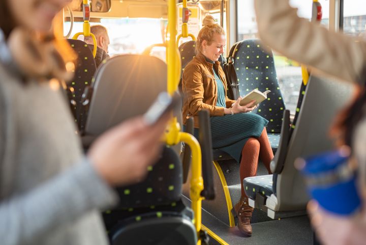 Happy woman reading a book while traveling by bus