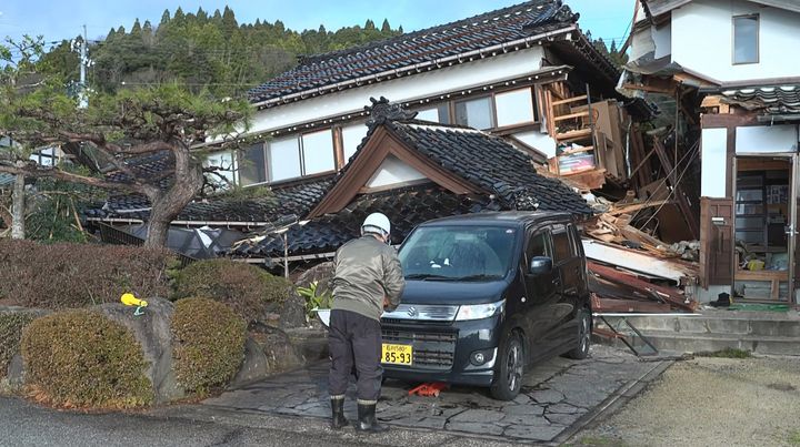 This screen grab from AFPTV video footage taken on Jan. 2, 2024, shows a man standing in front of a damaged house in Wajima, Ishikawa prefecture, a day after a major 7.5 magnitude earthquake struck the Noto region in Ishikawa prefecture.