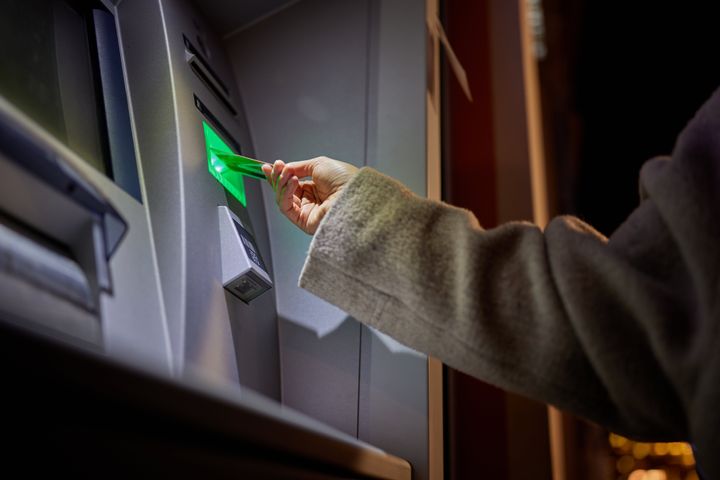 Close up of unrecognizable person withdrawing money from ATM.