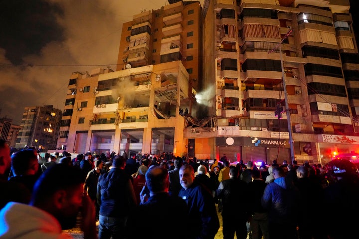 People gather outside a damaged building following a massive explosion in the southern Beirut suburb of Dahiyeh, Lebanon, Tuesday, Jan. 2, 2024. An explosion killed Saleh Arouri, a top official with the Palestinian militant group Hamas and three others, officials with Hamas and the Lebanese group Hezbollah said. (AP Photo/Bilal Hussein)