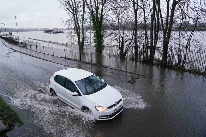 A vehicle drives through standing water close to a flooded Worcester racecourse, as heavy rain continues to fall in Worcester. 