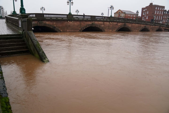 A person crosses Worcester Bridge as the river Severn continues to rise after persistent rain.