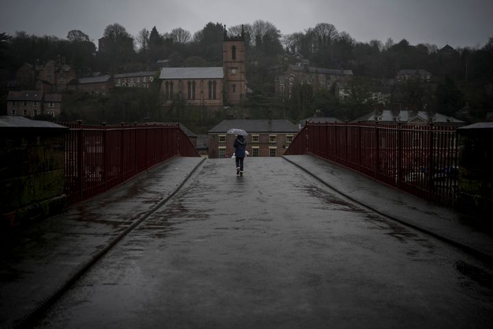 People walk across the iron bridge in the rain on January 02, 2024 in Ironbridge, England.