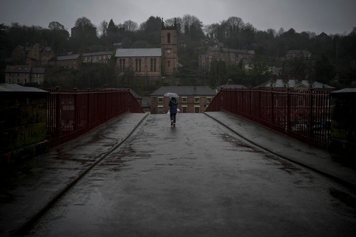 People walk across the iron bridge in the rain on January 02, 2024 in Ironbridge, England.