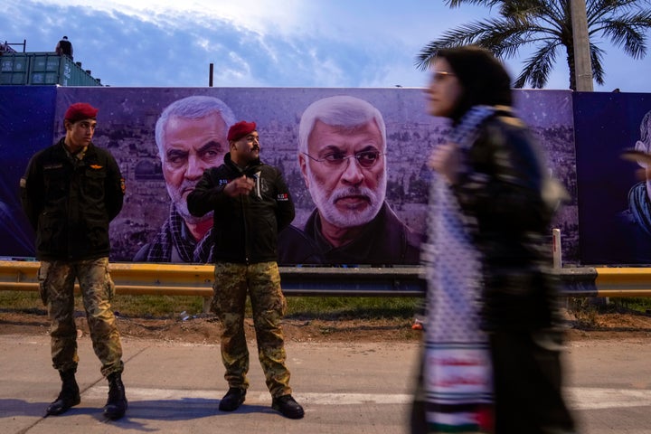 A woman holds a poster showing General Qassem Soleimani, left, head of Iran's Quds force and Abu Mahdi al-Muhandis, deputy commander of the Popular Mobilization Forces, during mark the fourth anniversary of the killing of Abu Mahdi al-Muhandis, deputy commander of the PMF and Gen. Qassem Soleimani, head of Iran's Quds forces, in Baghdad, Iraq, Tuesday, Jan. 2, 2024. Al-Muhandis and Soleimani were killed in an US air strike in Baghdad in 2020. (AP Photo/Hadi Mizban)