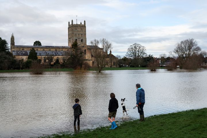People play with a dog in front of the Tewkesbury Abbey by fields flooded by the River Swilgate after it burst its banks, in Tewkesbury.
