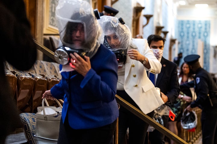 Reps. Sara Jacobs (D-Calif.), center, and Annie Kuster (D-N.H.), left, take cover as rioters attempt to disrupt the joint session of Congress to certify the Electoral College vote on Jan. 6, 2021.