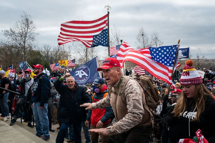 Ray Epps (center), in the red Trump hat, gestures to a line of law enforcement officers as people gather on the West Front of the U.S. Capitol on Jan. 6, 2021.