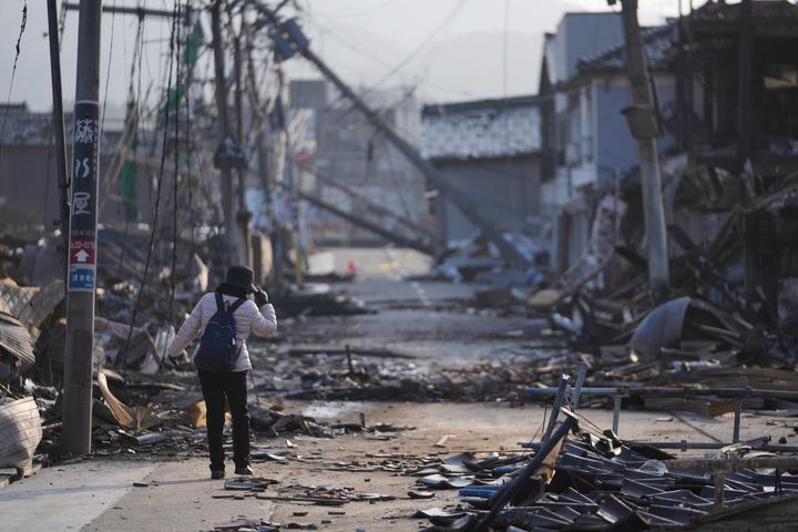 Ένα άτομο περπατάει σε έναν δρόμο με συντρίμμια κατεστραμμένων και καμένων κτιρίων στη Γουατζίμα στη χερσόνησο Νότο, απέναντι από τη Θάλασσα της Ιαπωνίας, βορειοδυτικά του Τόκιο, Σάββατο 6 Ιανουαρίου 2024, μετά τον φονικό σεισμό της Δευτέρας.