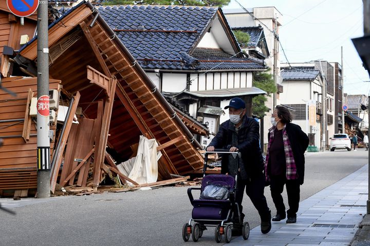 Residents walk past damaged buildings in the city of Wajima, Ishikawa prefecture, on January 5, 2024, after a major 7.5 magnitude earthquake struck the Noto region on New Year's Day. (Photo by Toshifumi KITAMURA / AFP) (Photo by TOSHIFUMI KITAMURA/AFP via Getty Images)