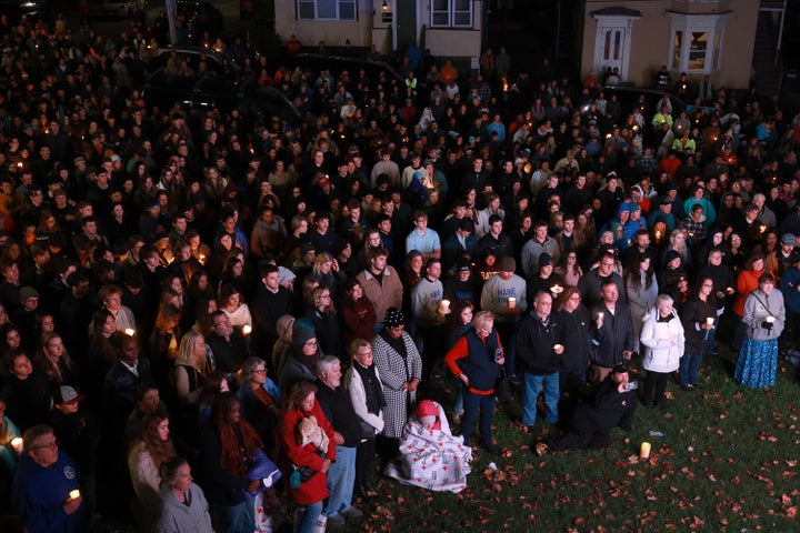 A crowd of people watch a television screen as it broadcasts from inside a church during a remembrance ceremony for those killed and injured in the October shooting.