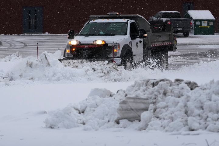 A school district snow plow cleans the school parking lot as a winter storm arrives in Wheeling, Ill., Friday, Jan. 12, 2024. (AP Photo/Nam Y. Huh)
