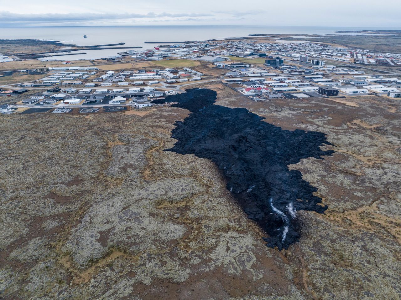 An aerial view of the lava field with inactive southern fissure next to the town.