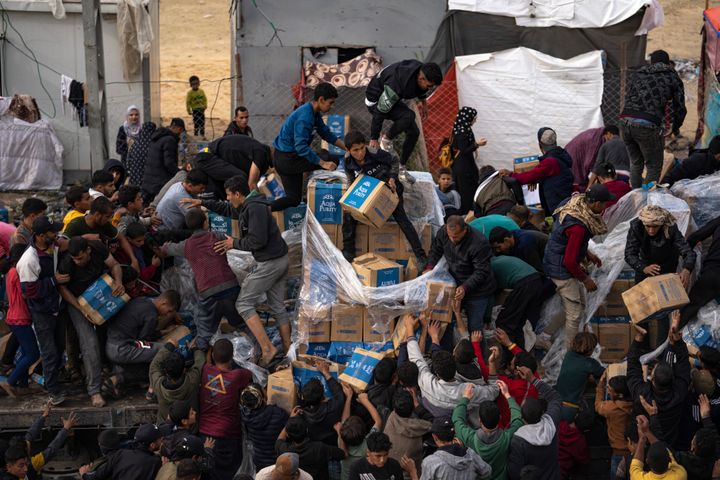 Desperate Palestinians grab boxes from a humanitarian aid truck as it crossed into the Gaza Strip in Rafah, Sunday, Dec. 17, 2023.