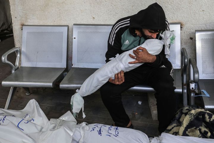 (EDITORS NOTE: Image depicts death.) A man holds the body of a small child as he and others mourn while collecting the corpses of friends and relatives killed in an airstrike on January 13, 2024 in Rafah, Gaza. Despite Israel's recent troop drawdown in Gaza and the discussion of postwar plans by an Israeli cabinet minister, the country has continued its intensive bombardment of the Gaza Strip, particularly in the territory's south, as it seeks to destroy Hamas.