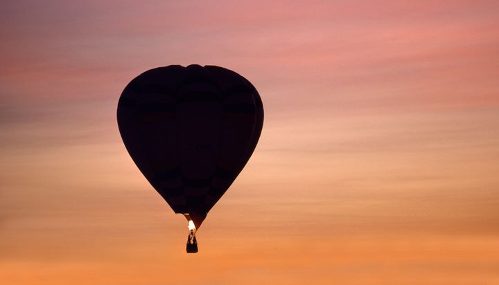 The hot air balloon was carrying five people when it crashed early Sunday. A similar hot air balloon is seen floating near Phoenix, Arizona, at sunset.