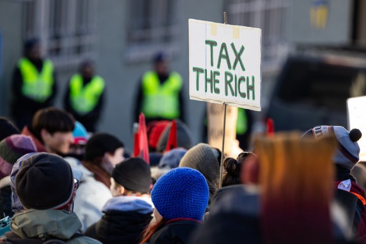 世界経済フォーラムの年次総会が開かれるスイス・ダボスで行われた気候正義を訴える抗議活動。「富裕層に課税せよ」というプラカードを掲げられている（2024年1月14日）