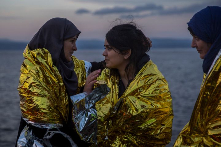 Τρεις γυναίκες φορούν θερμικές κουβέρτες που τους παρείχαν εθελοντές, αφού έφτασαν με λέμβο στην Λέσβο, μαζί με άλλους πρόσφυγες και μετανάστες, από τις ακτές της Τουρκίας, την Τρίτη 24 Νοεμβρίου 2015.