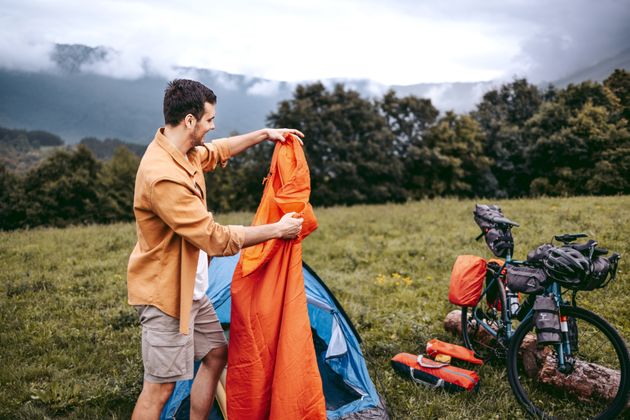 Young handsome camper setting up his sleeping bag for camping