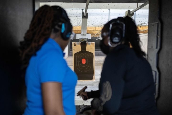 Vernice Howard (right) who started classes after a neighbor was assaulted at gunpoint, prepares to fire a Glock handgun as firearms instructor Taniece Reed, CEO and founder of Pretty Shooters Firearms Training, looks on at the Maryland Small Arms Range in Upper Marlboro, Maryland, on March 19, 2023.