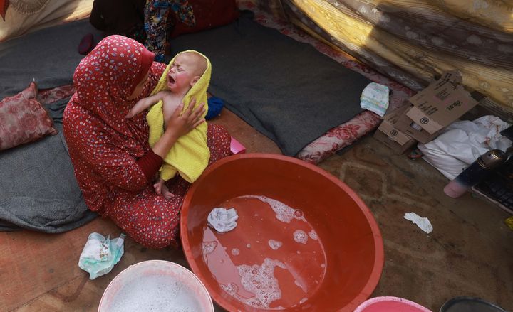 A woman dries a baby in a towel after giving it a bath inside a tent at a camp for displaced Palestinians in Rafah in the southern Gaza Strip on Jan. 18.